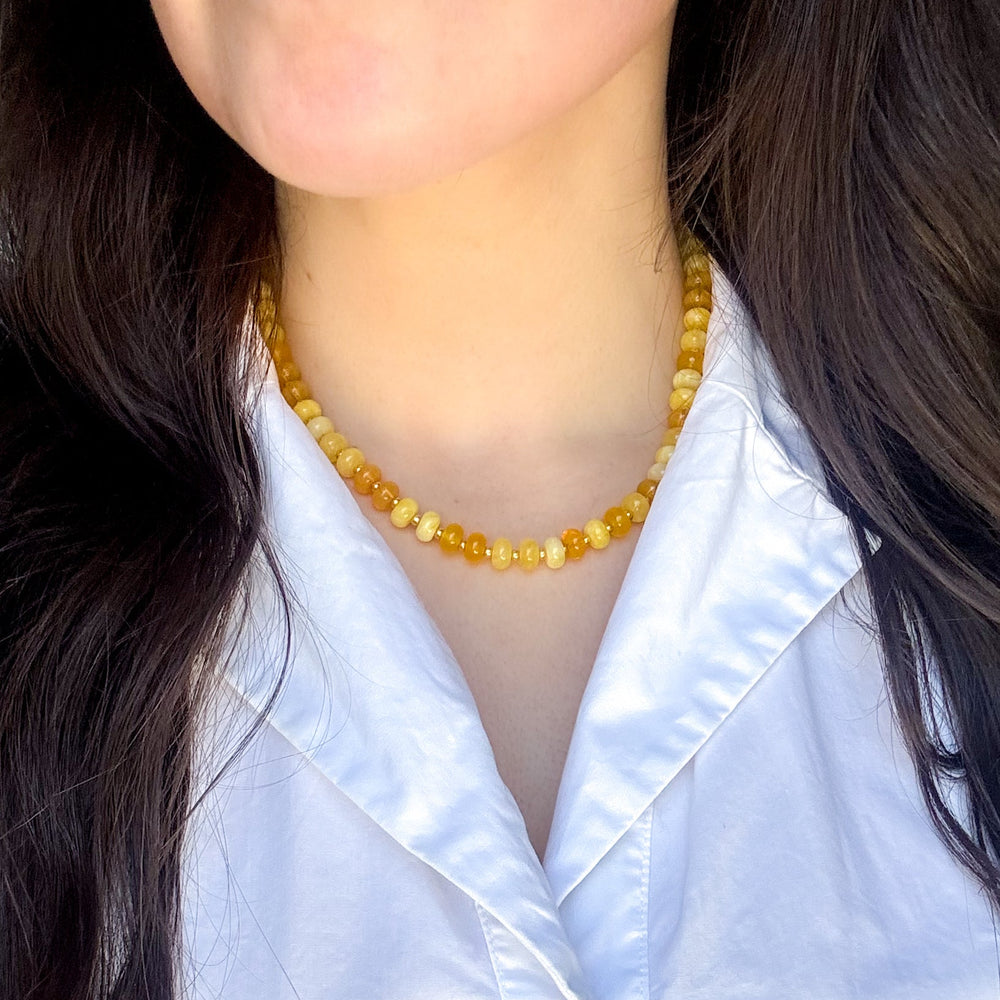 Person wearing a yellow beaded necklace with a white shirt