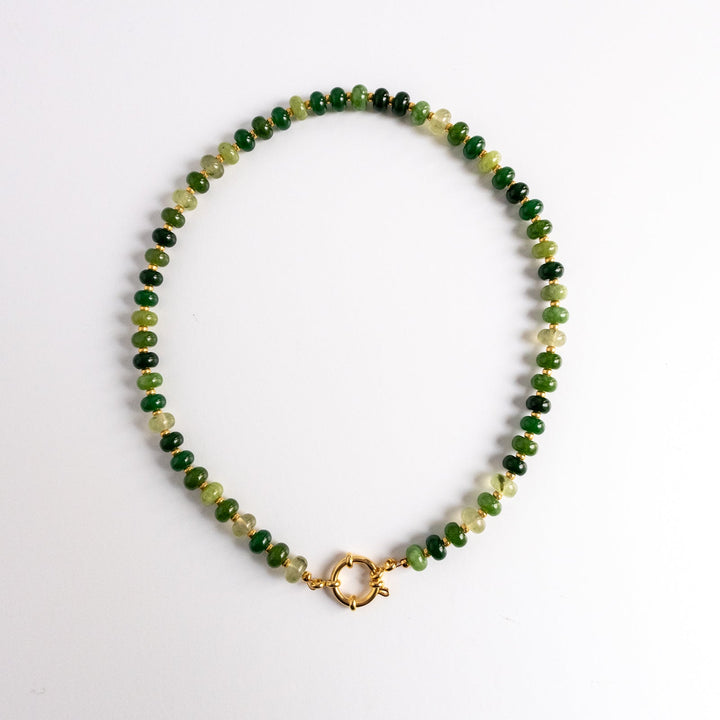 Necklace with green and gold beads on a white background