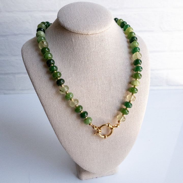 Green beaded necklace on a beige bust against a white background