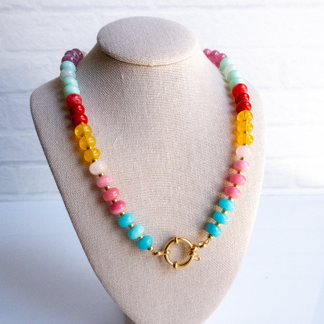 Colorful beaded necklace on a beige bust against a white background