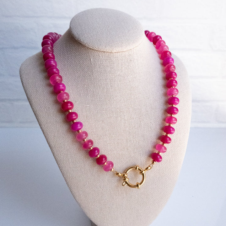 Pink beaded necklace on a white mannequin bust with a white background