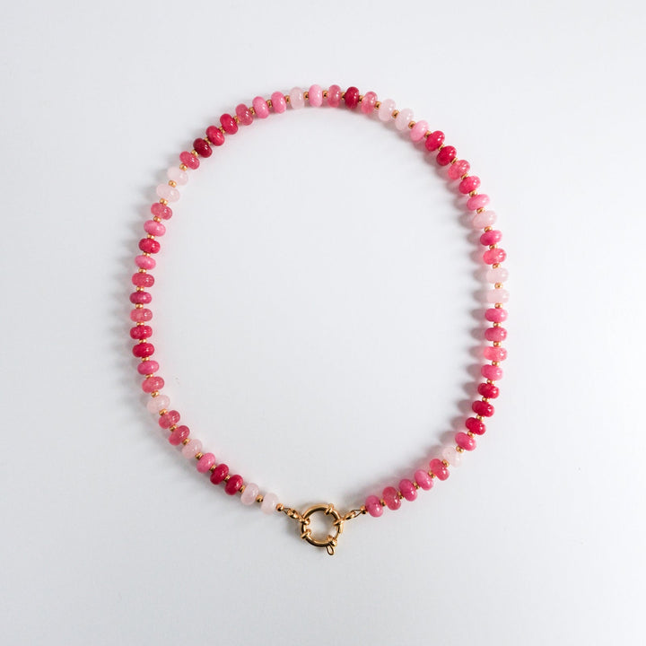 Beaded necklace with pink and white beads on a light gray background