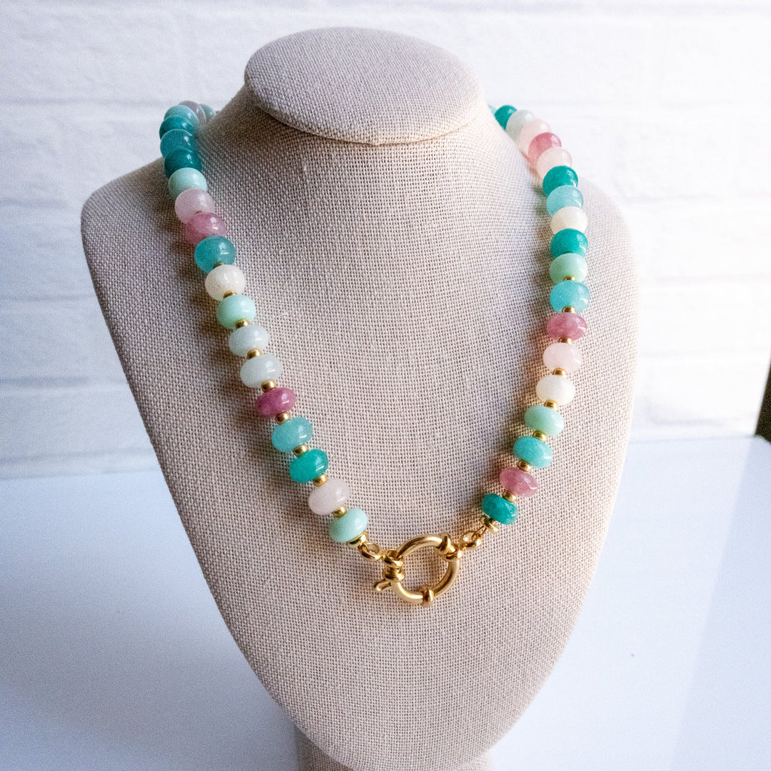 Necklace with colorful beads and a gold clasp on a beige bust against a white background