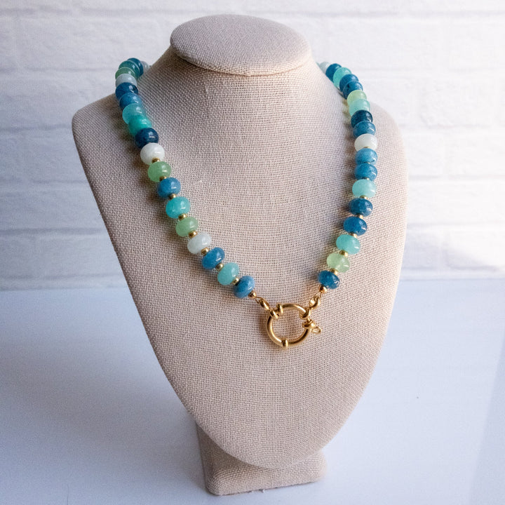 Necklace with blue and green beads on a beige bust against a white background