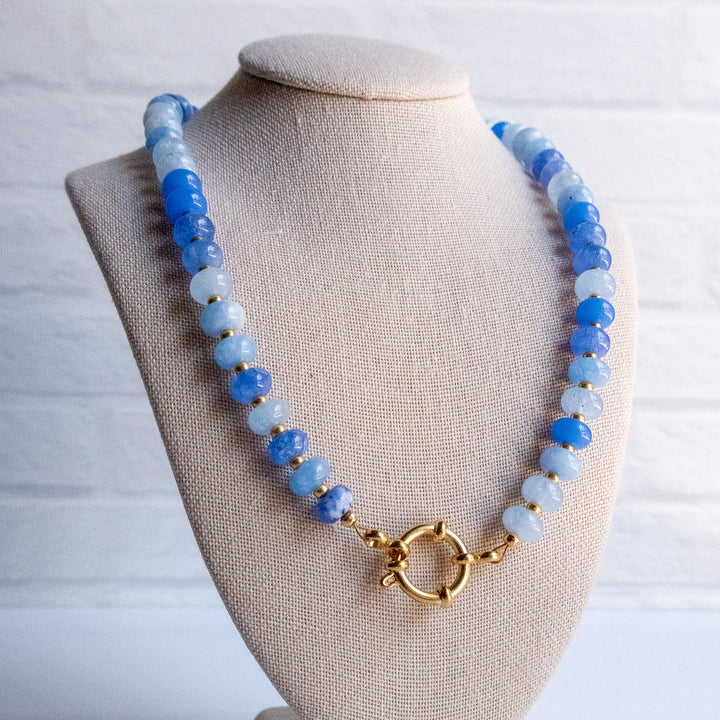 Necklace with blue and white beads on a beige bust against a light background
