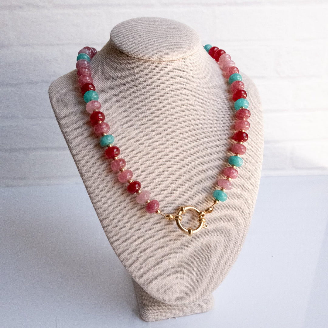 Necklace with red and turquoise beads on a beige bust against a white background
