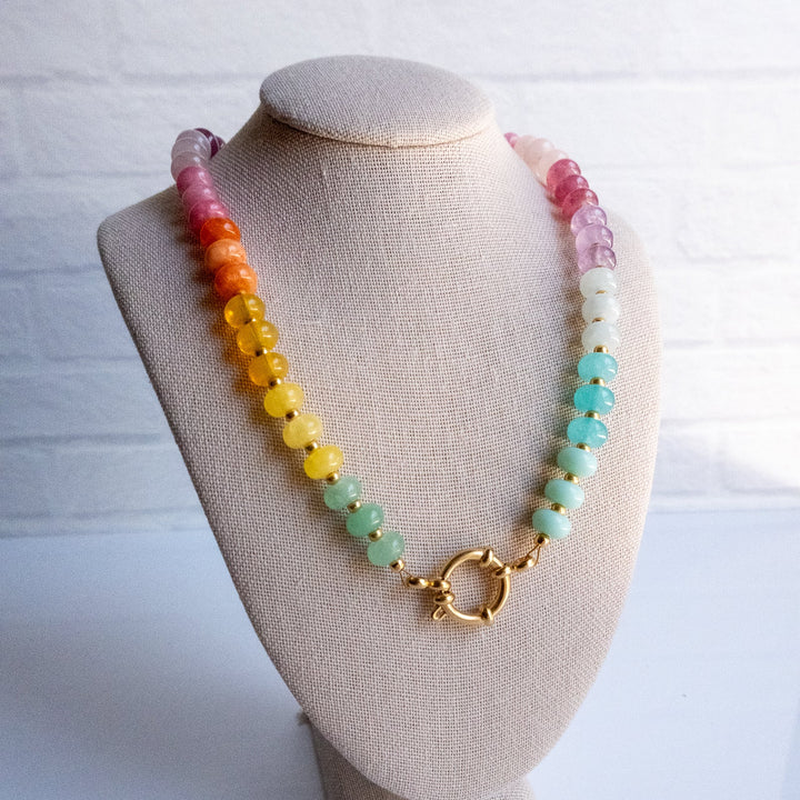 Necklace with colorful beads on a beige bust against a white background