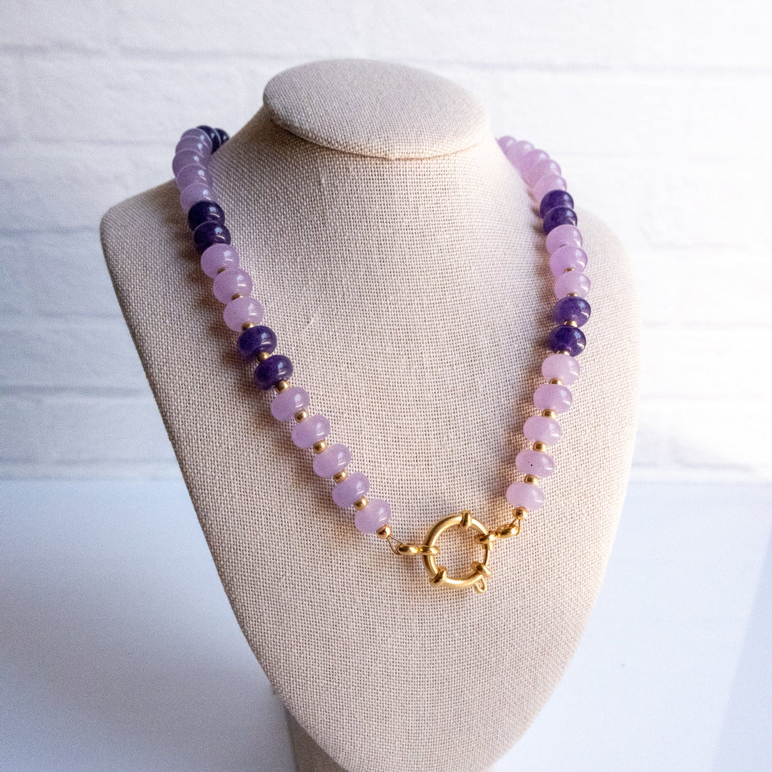 Necklace with purple and pink beads on a beige mannequin bust against a white background