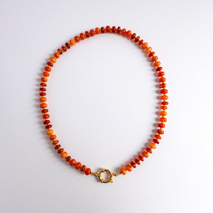 Necklace with orange beads and a gold clasp on a white background