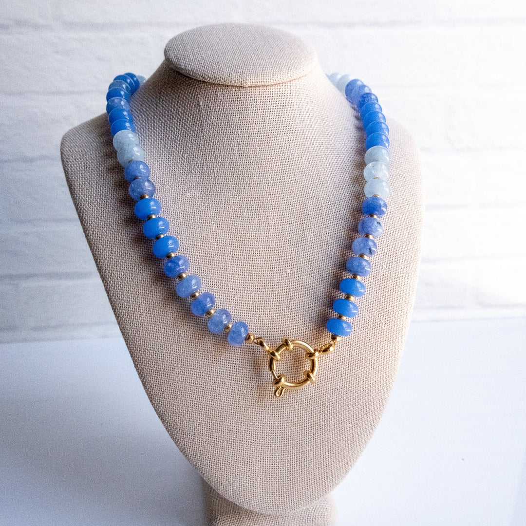 Blue beaded necklace on a beige bust against a white background