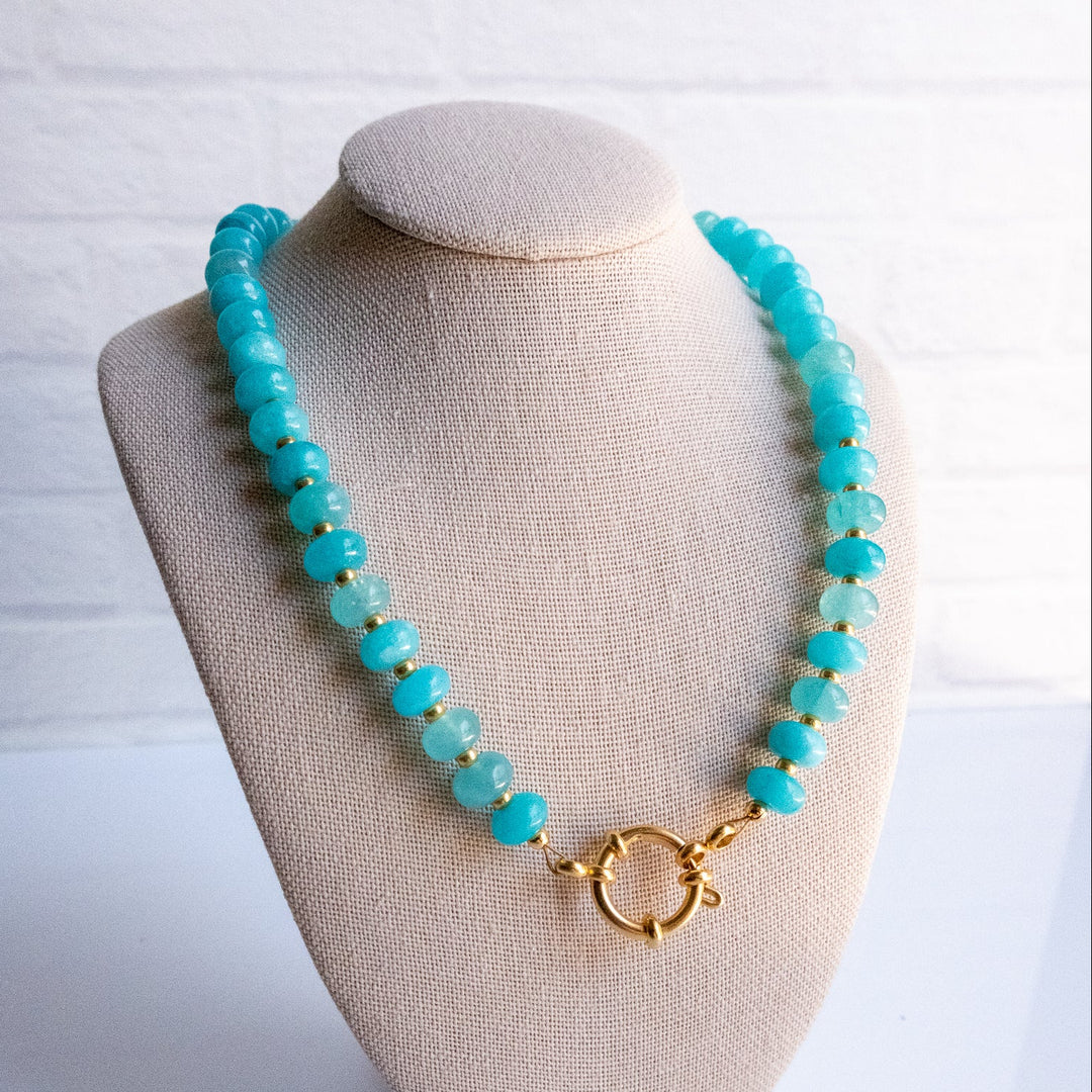 Turquoise beaded necklace on a beige bust against a white background