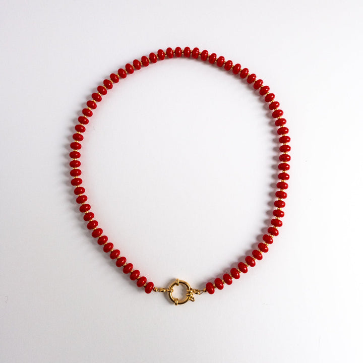 Red beaded necklace with a gold clasp on a white background